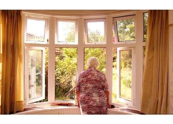 Elderly woman looking out of her front room window, London, UK. Photo by Bruce Detorres. Flickr.