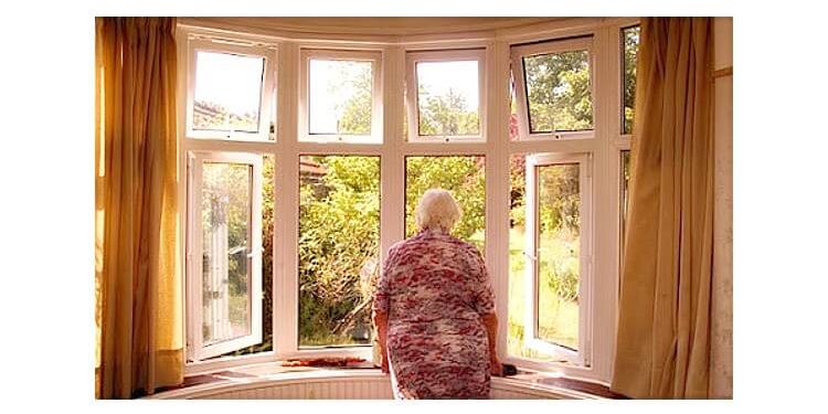 Elderly woman looking out of her front room window, London, UK. Photo by Bruce Detorres. Flickr.