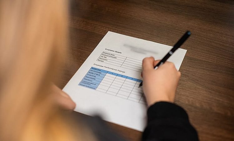 A woman filling in a claim form. Photo by Digits. Wikimedia.