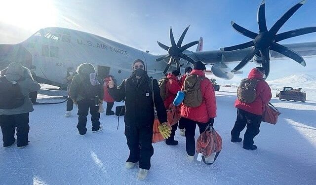 Marie Morrow, a marine transportation specialist with Military Sealift Command, poses for a photo in front of a ski-equipped LC-130 Hercules, at McMurdo Station, Antarctica