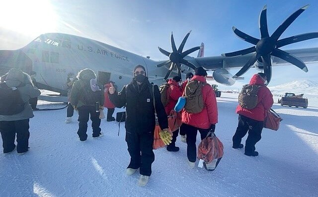 Marie Morrow, a marine transportation specialist with Military Sealift Command, poses for a photo in front of a ski-equipped LC-130 Hercules, at McMurdo Station, Antarctica