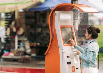 Young woman at a self-service booth in the rain. Photo by KissPR.