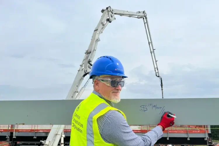 DIO’s David Salmond signing a steel beam on the roof of the new building. Photo by the MOD.