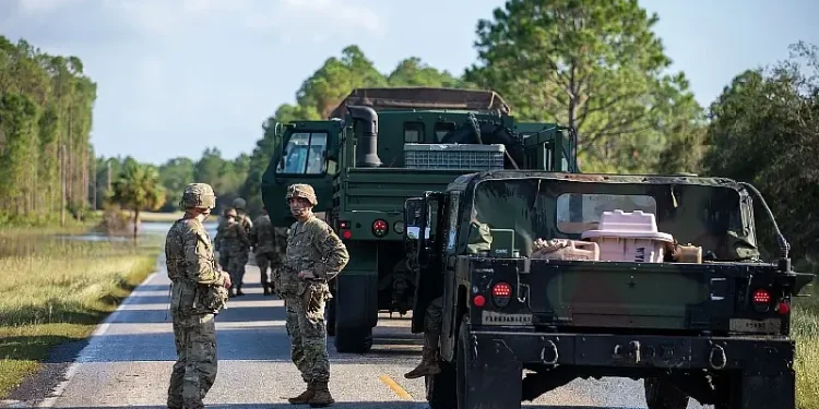 Soldiers clear road debris while assisting law enforcement at a checkpoint as part of their route clearing patrol in response to Hurricane Helene in Cedar Key, Fl. Photo by Army LT. Miles.