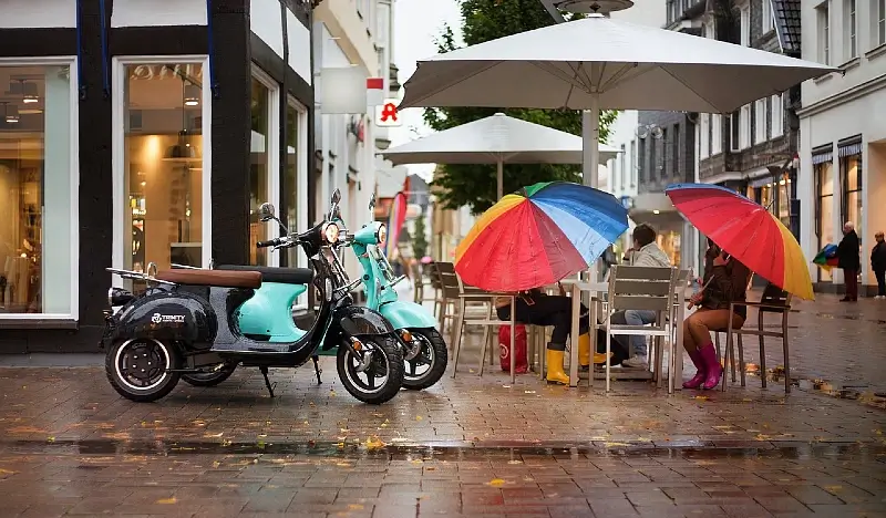 Electric scooters on a rainy day. Cafe culture. Photo by Trinity ElektroRoller.