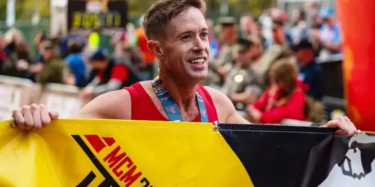 Marine Corps Maj. Kyle King poses for a photo with the finish line banner after winning the 49th Marine Corps Marathon in Arlington, Va., Oct. 27, 2024. Photo by Shannon Collins.