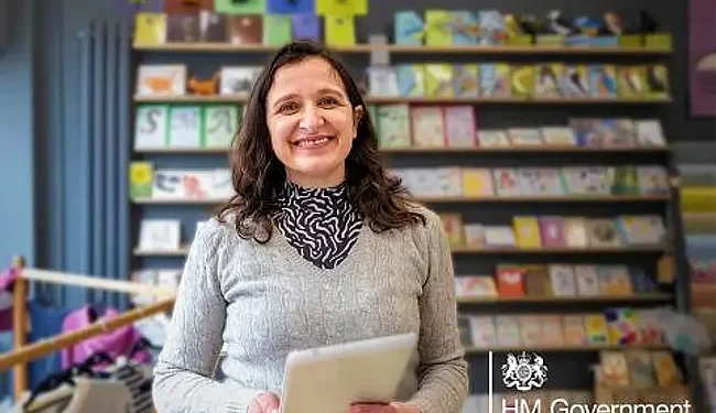 Voluntary NICs. Smiling woman with documents. Photo by HM Revenue & Customs
