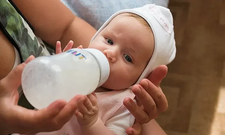 Baby and baby milk bottle. Photo by Vyacheslav Argenberg.