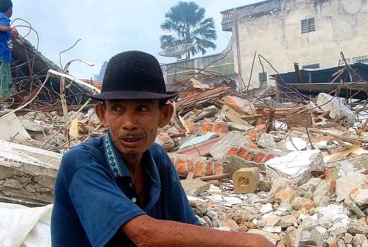 Man looks over his Nias neighbourhood following the 2004 Indian Ocean Tsunami. Indonesia, 2005. Photo by Department of Foreign Affairs and Trade.