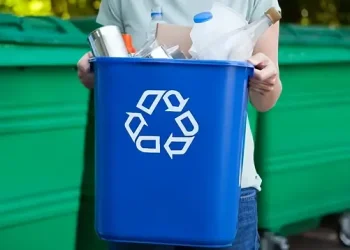 Woman carrying a blue recycling bin. Photo by DEFRA.