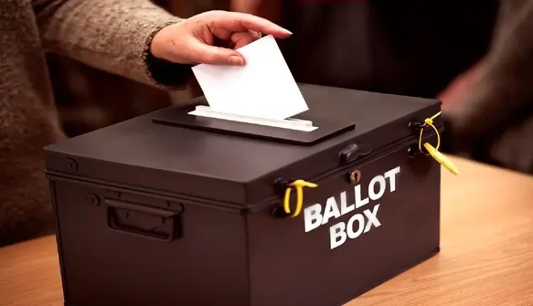 A ballot box with a lady voting. Photo by Getty Images.