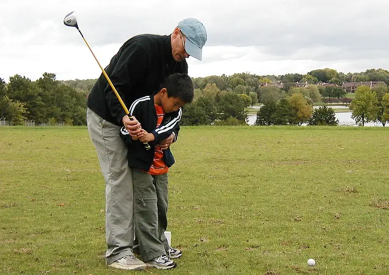Young boy having a golf lesson. Photo by Katatonic.