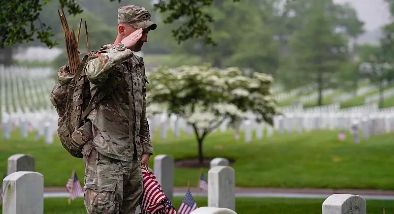 A soldier assigned to the 3rd U.S. Infantry Regiment salutes a Medal of Honor recipient's headstone in Arlington National Cemetery during Flags In, Arlington, Va., May 22, 2025. Photo by Sgt. Nathan Winter.