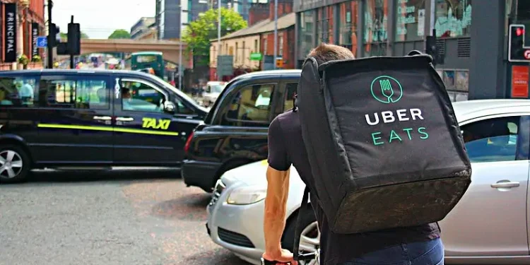 UBER Eats Delivery Cyclist Riding Through a Busy Oxford Road in Manchester. Photo by Shopblocks.