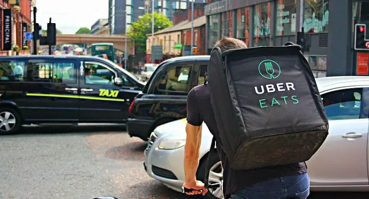 UBER Eats Delivery Cyclist Riding Through a Busy Oxford Road in Manchester. Photo by Shopblocks.