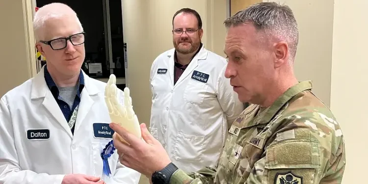 The Defense Logistics Agency Product Test Center Analytical employees Edward Dalton, engineer, and Mike McClain, artificial hand model concept to Army Brig. Gen. Sean P. Kelly. Photo by Mathews II.