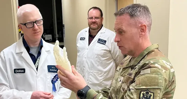The Defense Logistics Agency Product Test Center Analytical employees Edward Dalton, engineer, and Mike McClain, artificial hand model concept to Army Brig. Gen. Sean P. Kelly. Photo by Mathews II.