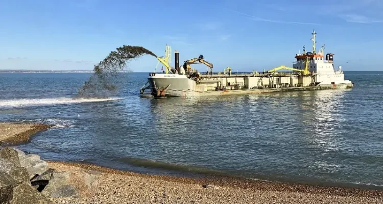 Shingle sprayed by the Sospan Dau will naturally settle into the right places through tidal action. Photo by the Environment Agency.