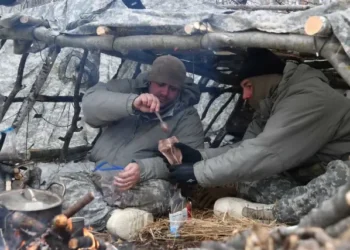 Air National Guard Security Forces specialists eat cold-weather meals ready to eat in a thermal shelter at Camp Ripley Training Center, Minn. Photo by Flanagan.