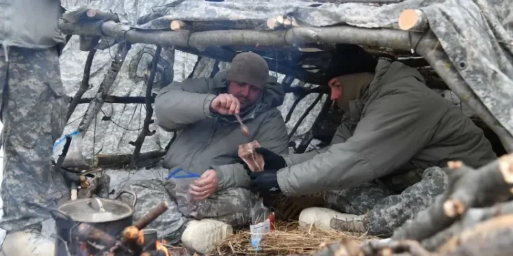 Air National Guard Security Forces specialists eat cold-weather meals ready to eat in a thermal shelter at Camp Ripley Training Center, Minn. Photo by Flanagan.