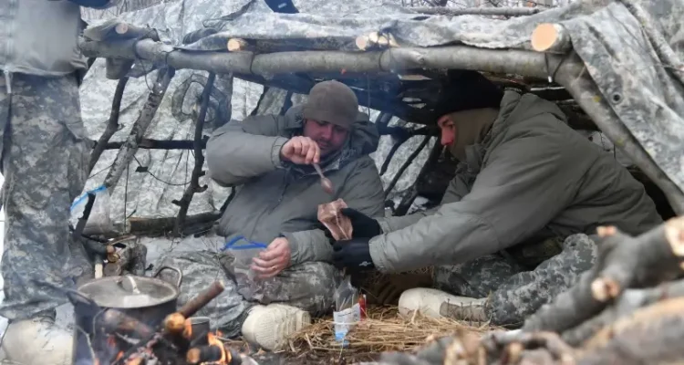 Air National Guard Security Forces specialists eat cold-weather meals ready to eat in a thermal shelter at Camp Ripley Training Center, Minn. Photo by Flanagan.