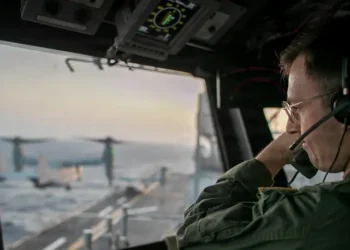A naval officer aboard USS Tripoli oversees flight operations from the control tower as the amphibious assault ship sails in the Arabian Sea. Photo by the US Navy.