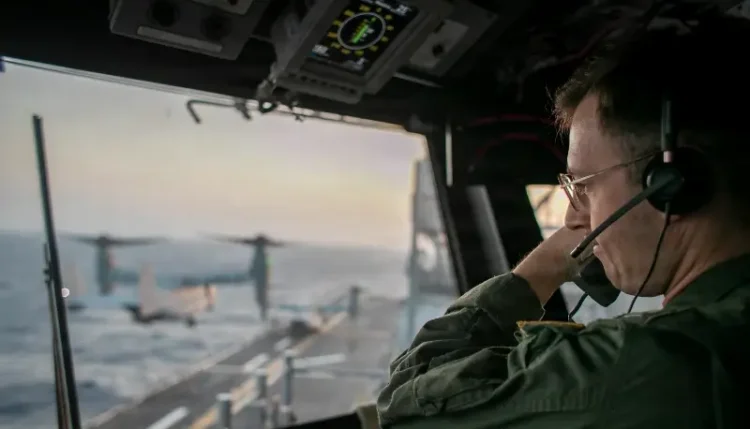 A naval officer aboard USS Tripoli oversees flight operations from the control tower as the amphibious assault ship sails in the Arabian Sea. Photo by the US Navy.